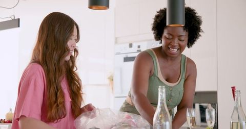 Happy friends tidying after party in modern kitchen