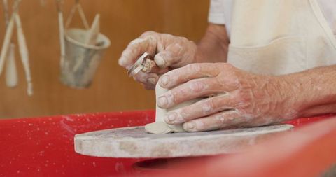 Senior man skillfully shaping clay in pottery workshop