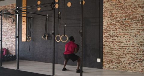 African American Man Lifting Medicine Ball in Industrial Gym Setting