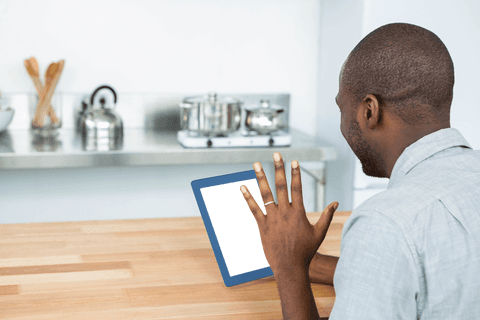 Transparent cutout of man looking at tablet in kitchen
