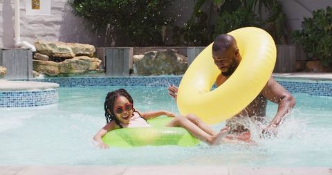 Father and daughter enjoying pool day with inflatable rings