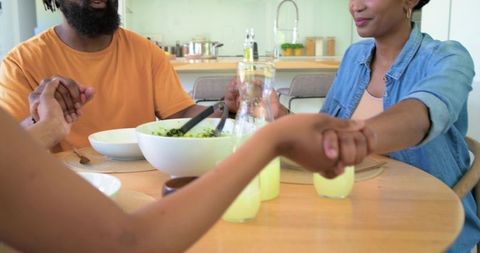 African family holding hands around dining table sharing meal and warm togetherness