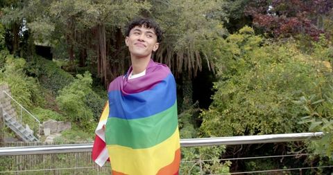 Young Man Draped in Rainbow Pride Flag Outdoors