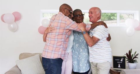 Senior friends celebrating cancer survivor with hugs at home
