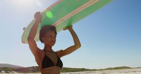 Smiling Female Surfer Carrying Surfboard at Sunny Beach