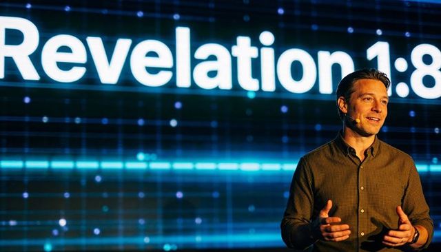 Pastor delivering sermon with revelation 1:8 led backdrop on modern church stage