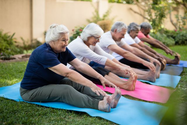 Group of seniors stretching on yoga mats in a park, promoting active aging and healthy lifestyle. Ideal for use in articles or advertisements related to senior fitness, community wellness programs, and outdoor exercise classes for the elderly.