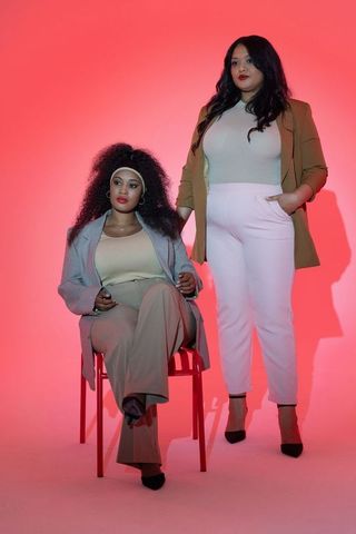 Diverse women posing in stylish blazers and heels with bold pink gradient lighting