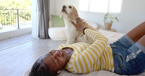 African American Woman Relaxing on Bed with Loyal Dog