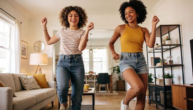 Dancing friends enjoying sunny living room party wearing casual summer outfits