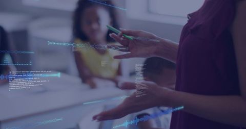 Educator gesturing with green pen and digital data overlays during classroom tech presentation