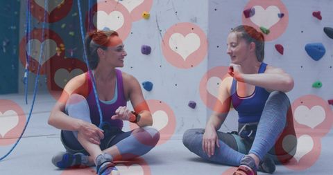 Two Women Fist Bumping at Climbing Gym Surrounded by Heart Icons