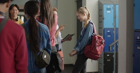 Teenage students smiling and conversing in school hallway