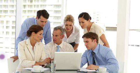 Corporate Team Collaborating on Laptop in Modern Glass Conference Room Planning Strategy
