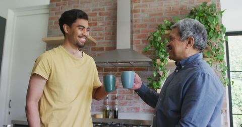 Father and Son Toasting Coffee Mugs in Kitchen Setting