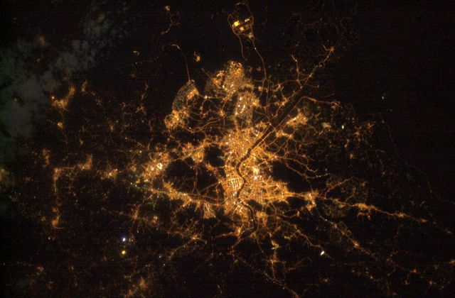 This image shows a breathtaking aerial night view of Seoul, South Korea, taken from the International Space Station on December 25, 2004. The brightly illuminated roadways, city center, and industrial complexes create a stunning contrast with the surrounding darker areas, which represent mountains and water bodies. Ideal for use in projects related to urban planning, night photography, city infrastructure, and educational materials on geographic information systems (GIS) and aerial photography.