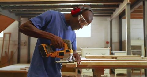 Skilled Craftsman Using Jigsaw for Woodworking in Atelier