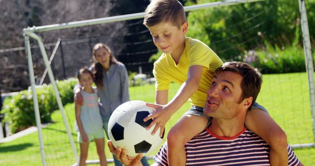 Father carrying son on shoulder playing soccer outdoors with family - Download Free Stock Images Pikwizard.com