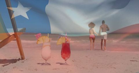 Couple Holding Hands on Beach with Refreshing Tropical Cocktails