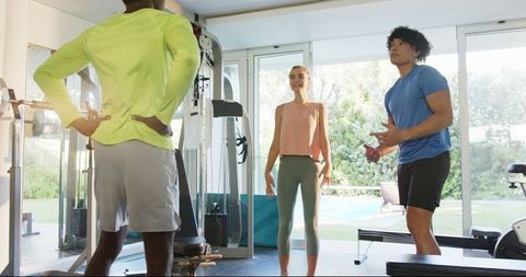 Young couple stretching with personal trainer in gym