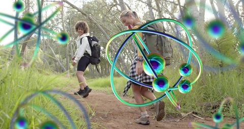 Two women hiking forest trail wearing backpacks and boots with neon orbital graphics