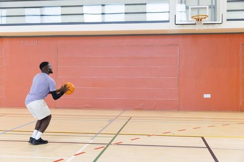 African american athlete practicing free throw on indoor basketball court