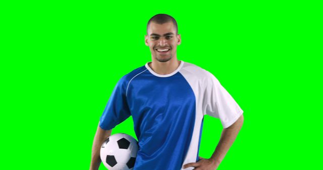 This image features a smiling soccer player in blue and white uniform, holding a soccer ball against a green screen background. It can be used for sports promotion, athlete features, soccer-related advertisements, and digital content creation with customizable backgrounds.