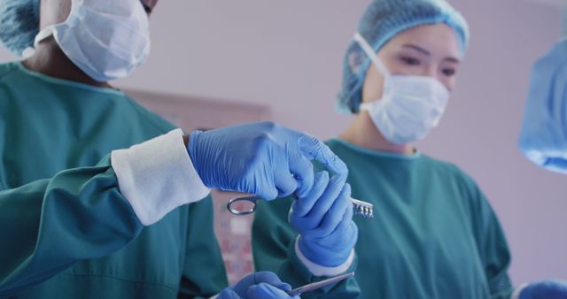 Image of diverse female surgeon and surgical assistants passing instruments during operation. Hospital, medical and healthcare services.