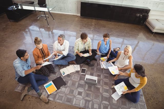 High angle view of business people working while sitting on floor in creative office