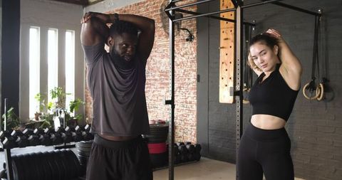Athletes Stretching Overhead Triceps in Industrial Gym Space