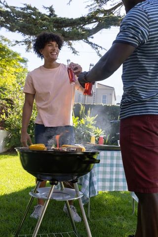 Friends Celebrating Summer Cookout by Charcoal Grill