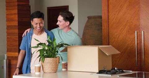 Male couple celebrating new home with coffee and embracing
