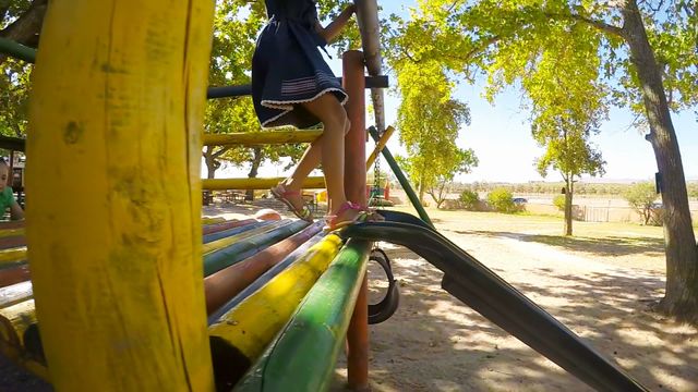 Children enjoying a sunny day at the park, climbing on playground equipment and having fun. This video can be used for promoting outdoor activities, children's products, and family-friendly locations or events.