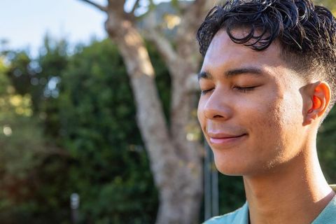 Serene young man enjoying nature with eyes closed and smile