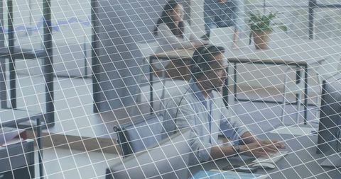 Employee typing at desktop through wire-grid partition in open-plan office