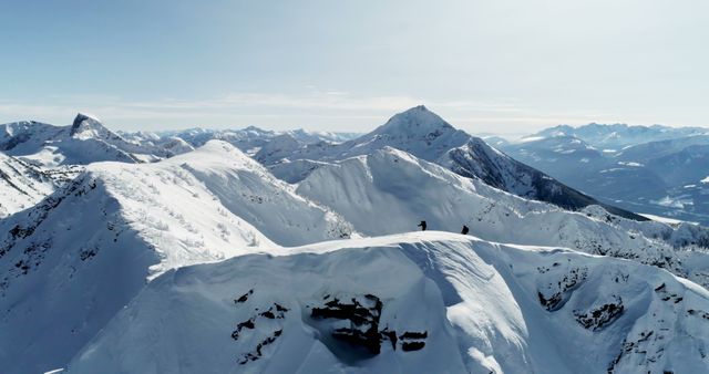 A lone adventurer stands atop a snowy mountain peak, with copy space. The vastness of the alpine landscape emphasizes the solitude and grandeur of mountaineering.