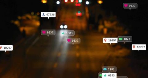 Blurred urban roadway at night receiving social media reaction bubbles over headlights