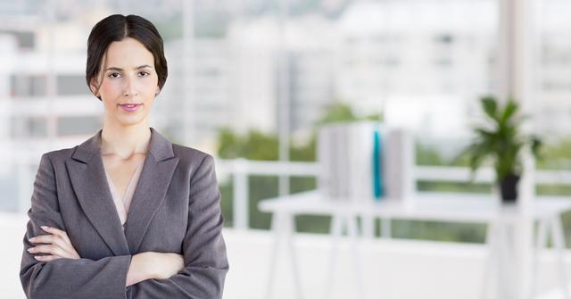 Portrait of a confident businesswoman standing with arms crossed in office - Download Free Stock Photos Pikwizard.com
