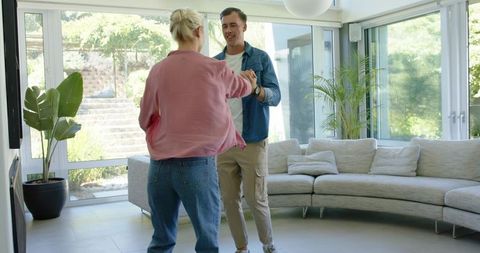 Couple dancing and twirling in sunlit modern living room with curved sectional sofa