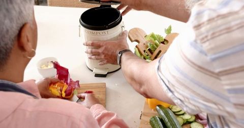 Couple Composting Vegetable Scraps at Kitchen Counter for Sustainable Living