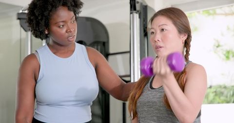 Fitness Trainer Coaching Woman Lifting Dumbbells for Arm Strength