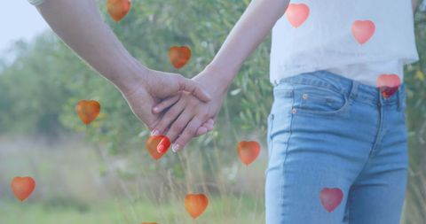Romantic couple holding hands with floating heart balloons