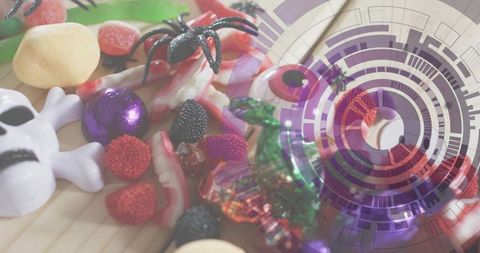 Halloween candy assortment on light wood tabletop with skull, spider and digital overlay