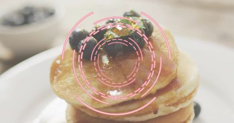 Fluffy pancake stack with blueberry topping and syrup, pink circular digital overlay