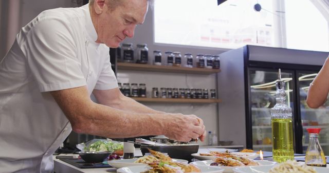 Senior chef is seen preparing a gourmet meal in a professional kitchen. This could be used for articles or advertisements related to culinary arts, professional cooking, restaurant profiles, or kitchen decor. Ideal for websites and publications focusing on high-end dining, culinary schools, and chef training programs.