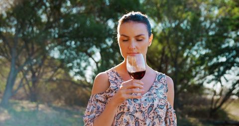 Serene Woman Enjoying Wine Outdoors in Natural Setting