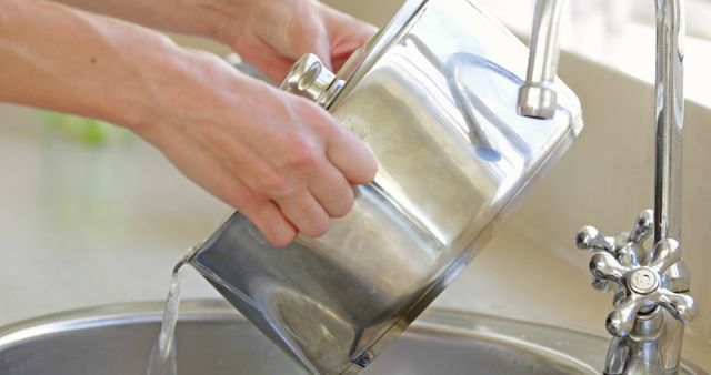 Person rinsing stainless steel pot in kitchen sink - Download Free Stock Images Pikwizard.com