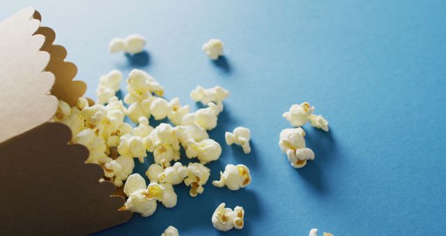 Close-Up of Popcorn Spilling from Box on Blue Background - Download Free Stock Images Pikwizard.com