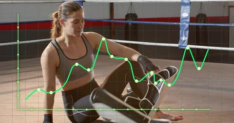 Female fighter adjusting kick pads in boxing ring with performance data overlay