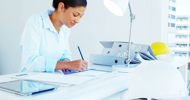 Female Architect Writing Plans at Office Desk - Download Free Stock Images Pikwizard.com